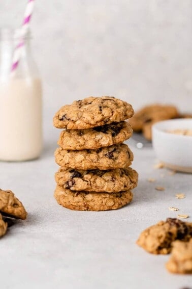 a stack of oatmeal raisin cookies with a glass of mail