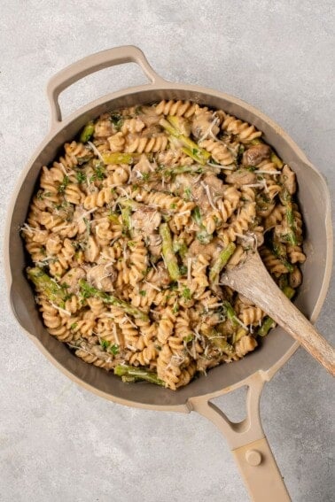 overhead image of creamy one pot pasta in pan topped with parmesan and spoon