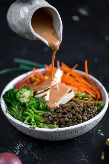 dressing being poured overed tofu