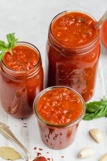 Homemade marinara sauce in jars with the ingredients and white background