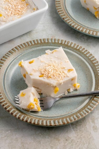 a slice of maja blanca topped with toasted coconut flakes on a blue plate