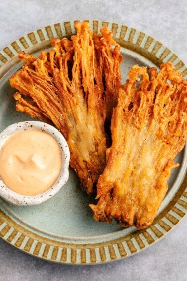 fried enoki mushrooms on a plate with a dipping sauce