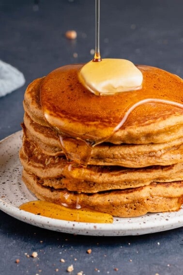 Vegan Gingerbread Pancakes with maple syrup and butter on white plate