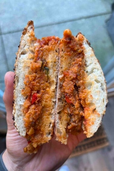 Ratatouille Parmesan sandwich sliced in half being held open