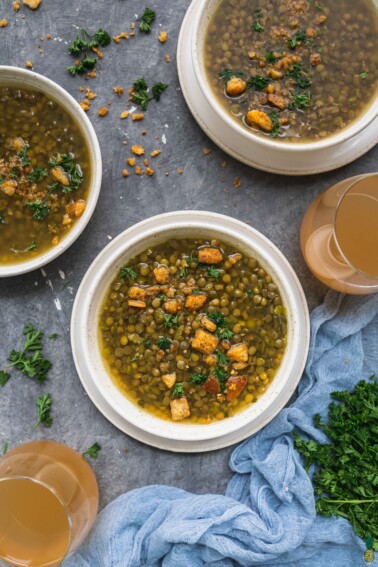 An overhead shot of a vegan lentil and split pea soup in a white bowl on a dark background by sweet simple vegan