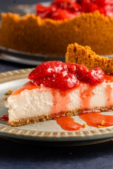 close up of vegan cheesecake with strawberry sauce on light blue plate