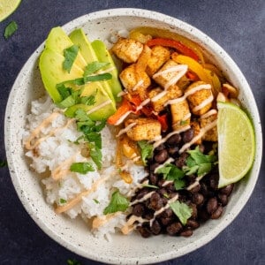 white bowl of tofu fajitas with black beans, lime and chipotle cream