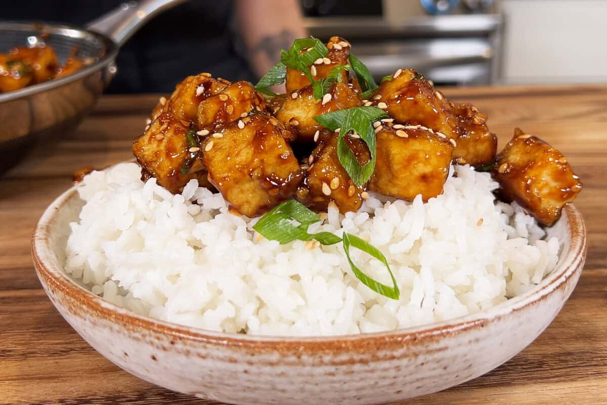 sticky sesame tofu on a bed of rice in a bowl