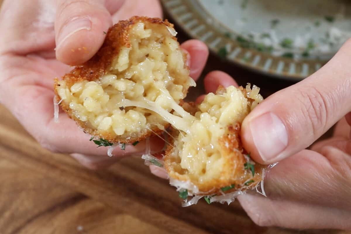 arancini being torn in half with the cheese pulling