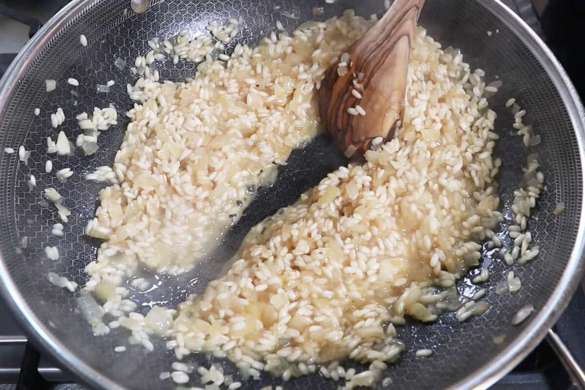 mixing risotto in wok with wooden spoon