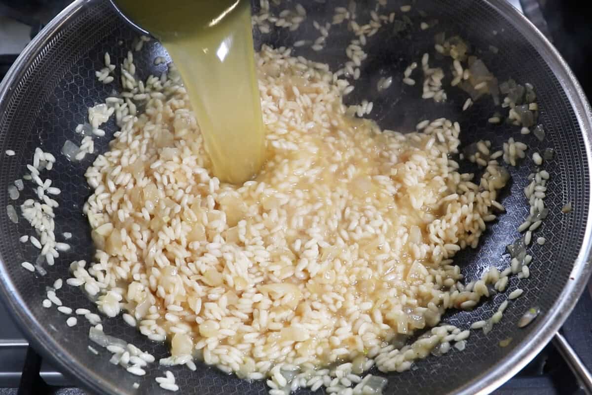 adding broth to rice in wok