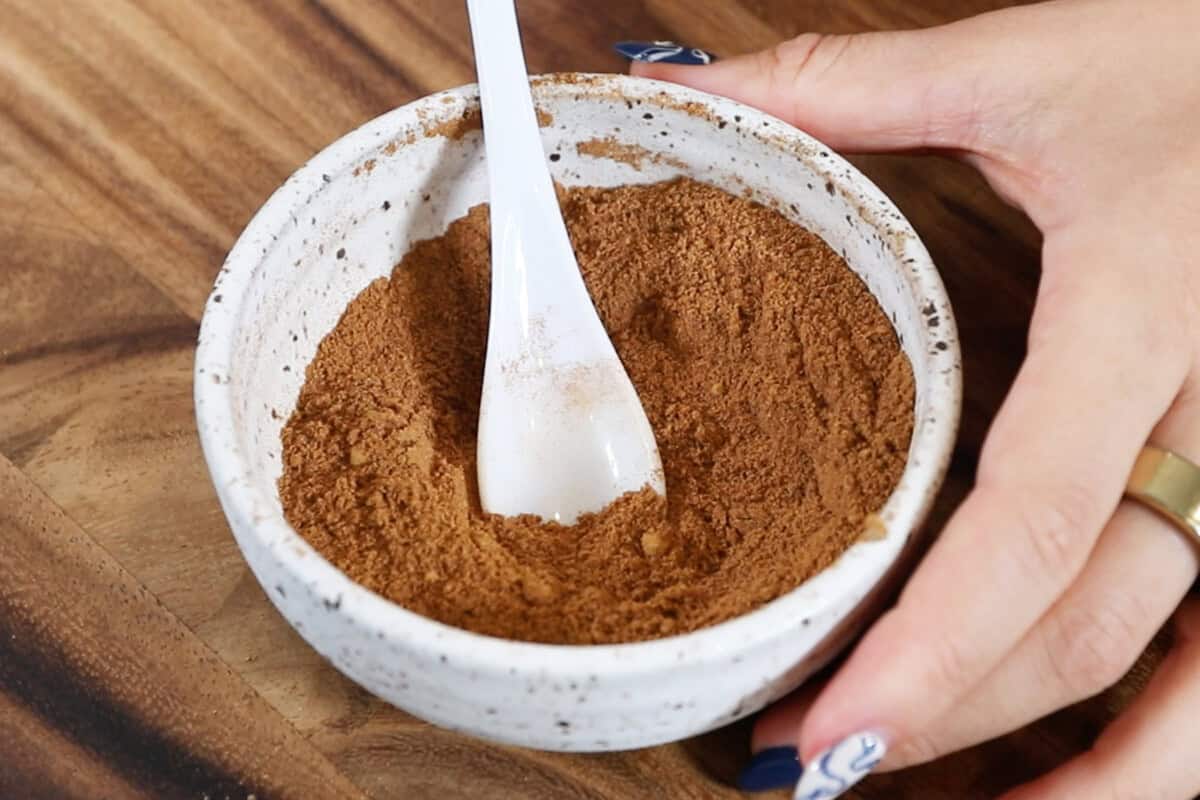 preparing homemade chai spice blend in white bowl