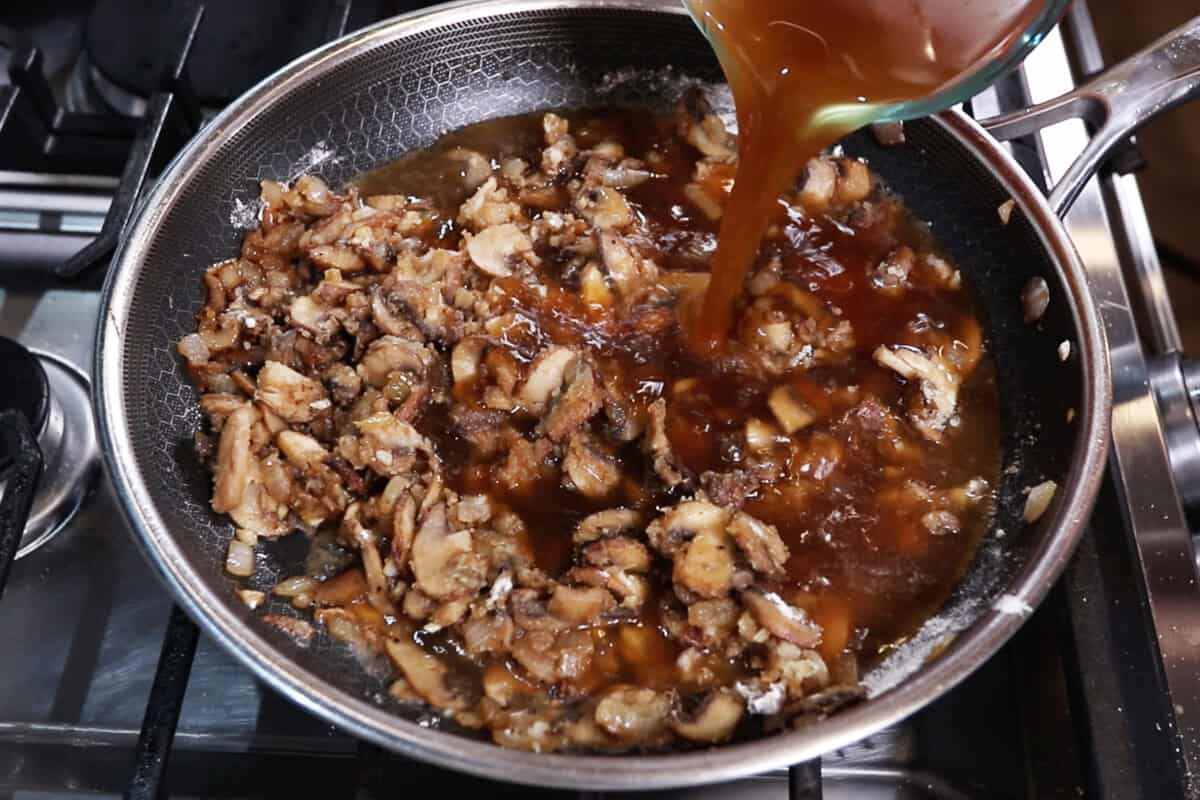 adding broth to the pan