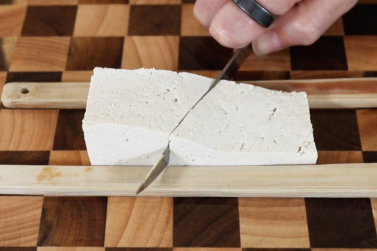 cutting slits into a slab of tofu