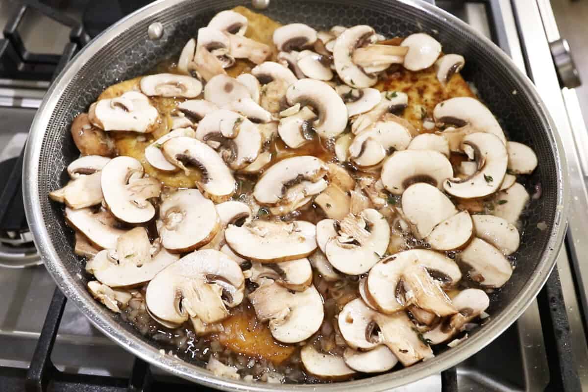 adding mushrooms to a large skillet