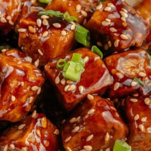 close up of sticky sesame tofu topped with green onions