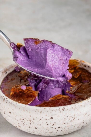 a scoop of Ube Creme Brûlée in a speckled white container