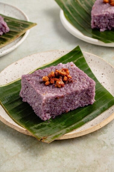 a slice of filipino biko rice cake on a banana leaf on white plate