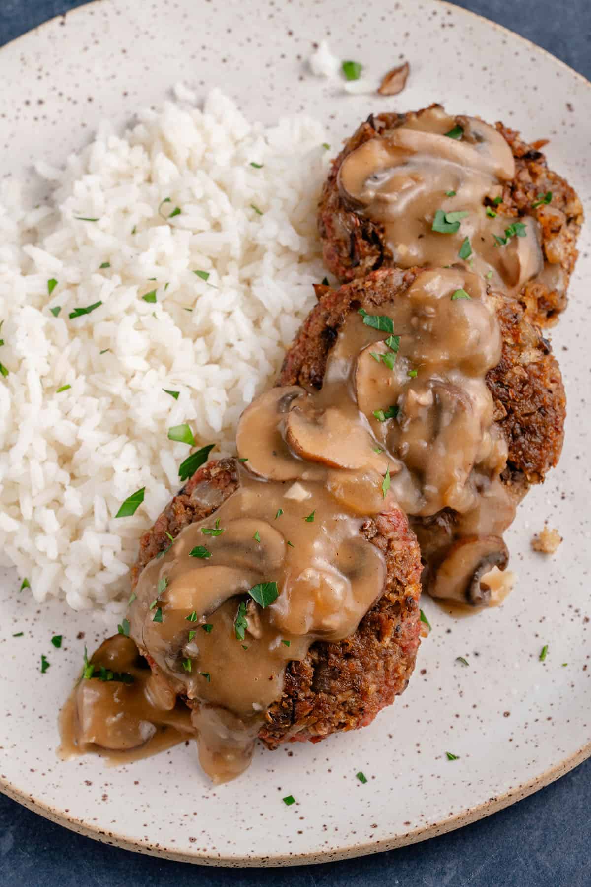 vegan filipino burger steak on a plate topped with mushroom gravy and served with rice