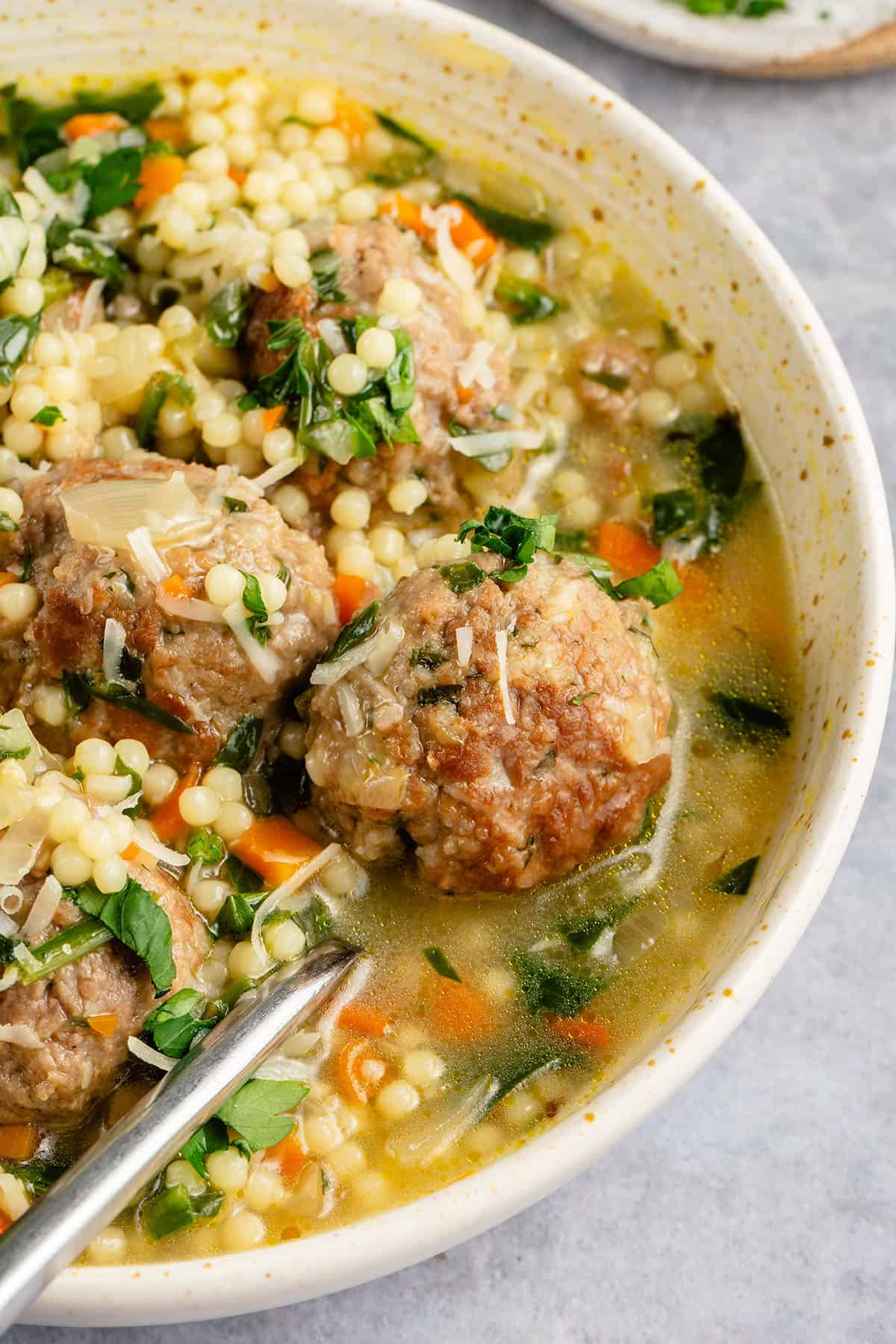 close up of bowl of vegan italian wedding soup topped with parmesan