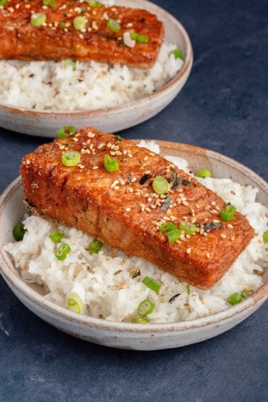 vegan salmon filet topped with green onions, sesame seeds, and seaweed on a bed of white rice