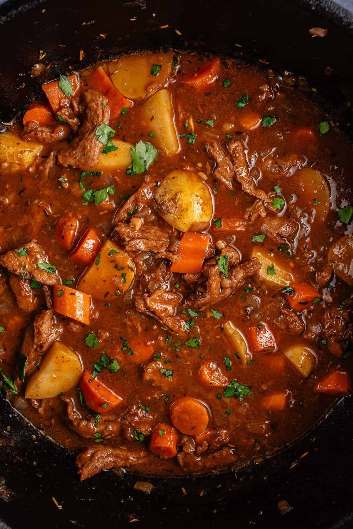 pot of vegan beef stew garnished with fresh parsley