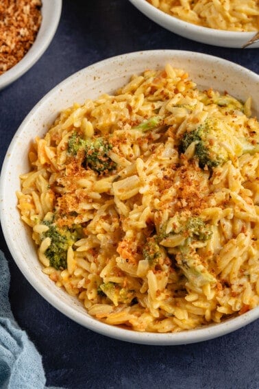 broccoli cheddar orzo with breadcrumbs in beige bowl