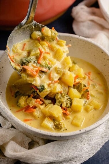 close up photo of creamy vegan broccoli potato soup being scooped into white bowl