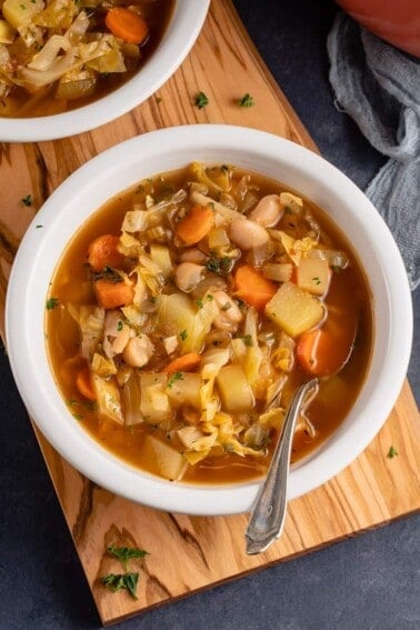 white bowl with vegan cabbage soup and metal spoon