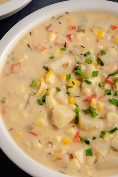 bowl of corn chowder with green onion garnish in a white bowl