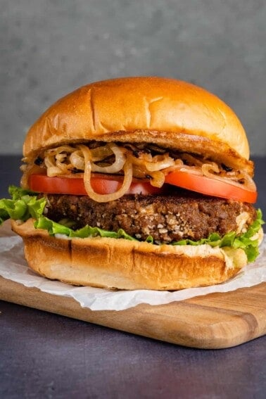 vertical close up photo of filipino adobo inspired burger on wooden board