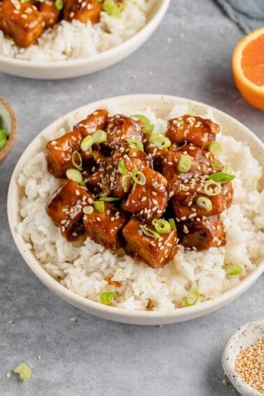 close up of saucy vegan orange tofu in a bowl with rice