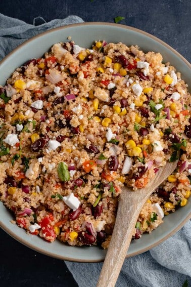 vegan quinoa salad in large blue bowl with wooden spoon