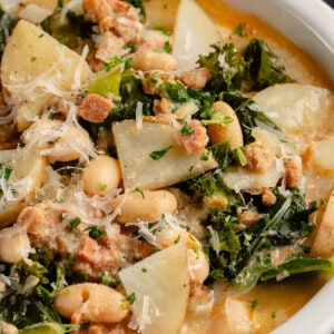 upclose image of vegan zuppa toscana topped with parmesan cheese in white bowl