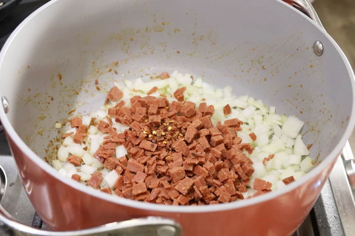 red pepper flakes and bacon being added to pot