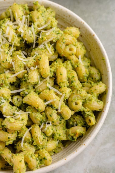 half a bowl of zucchini pesto pasta with dairy-free parm